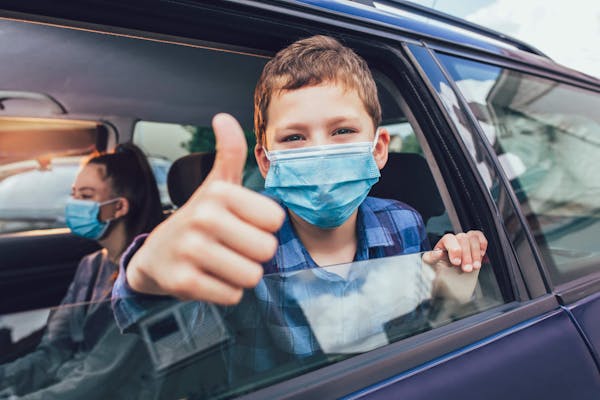 Children in medical masks inside car