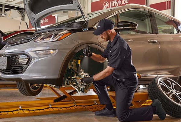 Jiffy Lube employee inspecting electric vehicle