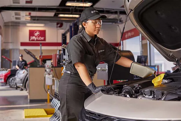 Jiffy Lube employee pouring oil into vehicle
