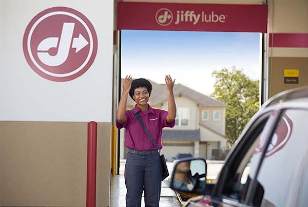 Jiffy Lube employee waving customer to pull up