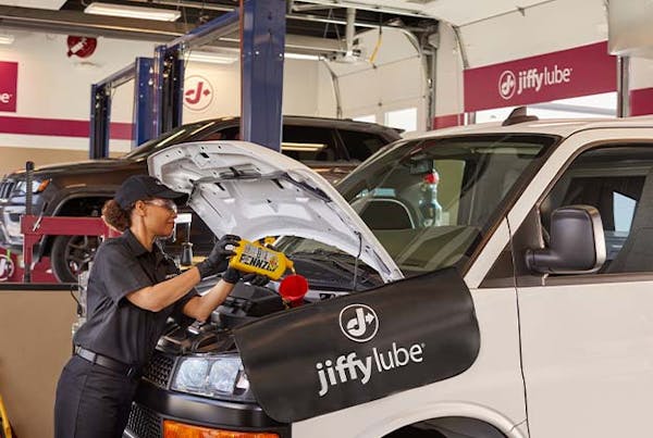 Jiffy Lube employee pouring Pennzoil oil into fleet vehicle
