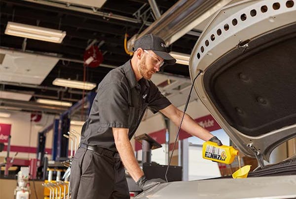 Jiffy Lube employee pouring Pennzoil oil into vehicle