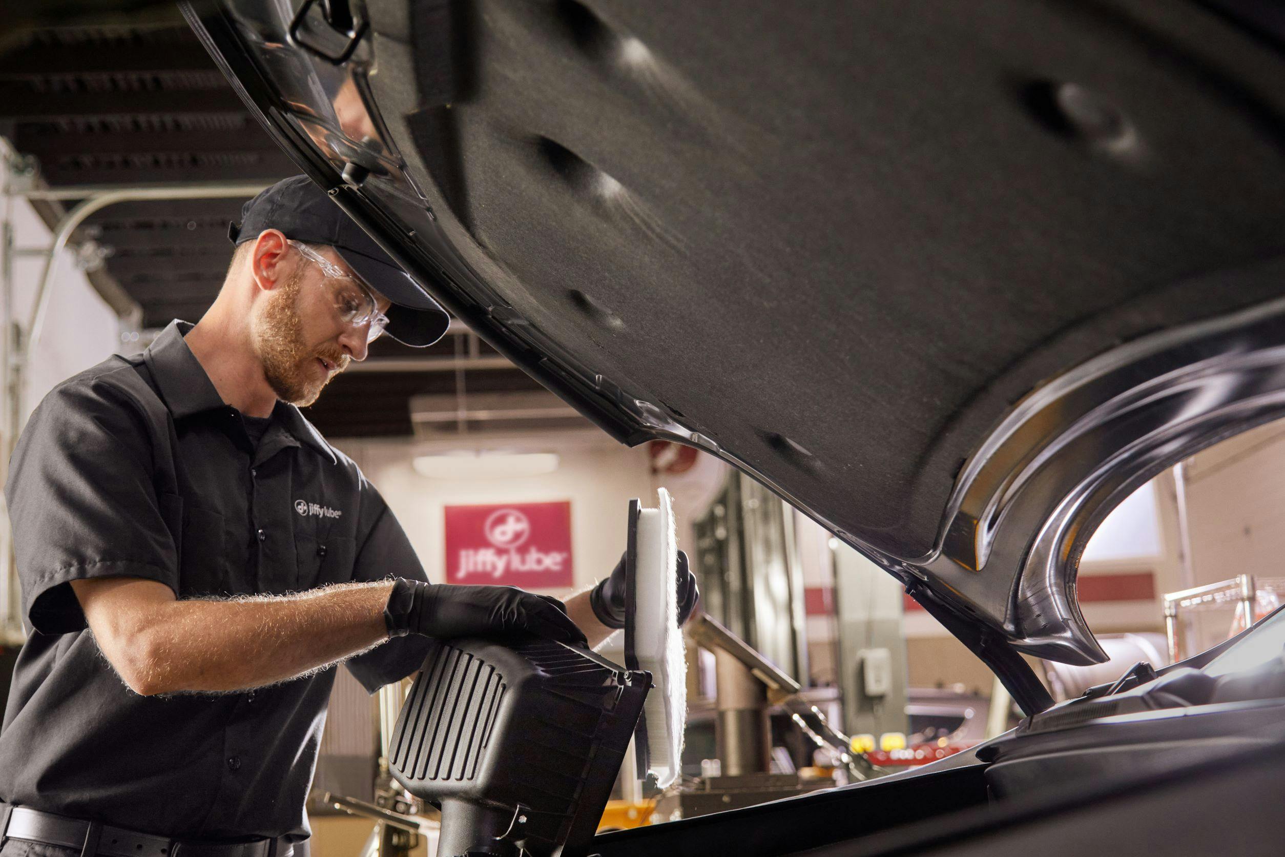 Technician member adding a new engine air filter to a car