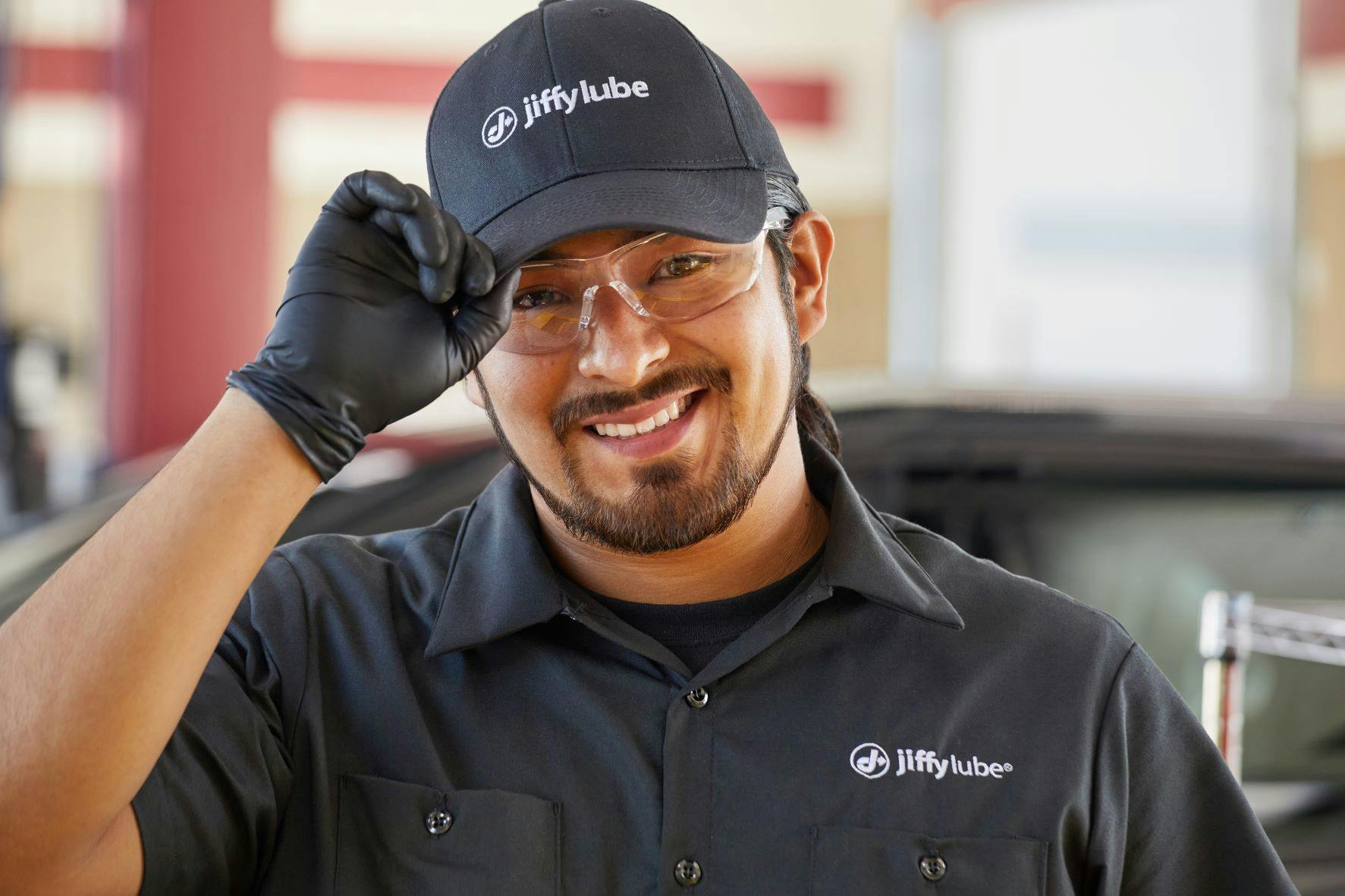 A Jiffy Lube service member with a warm, welcoming smile facing the camera, ready to check your tire pressure