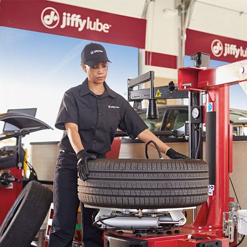 Jiffy Lube technician using a machine to balance a vehicle's tire, which helps prevent a tire 