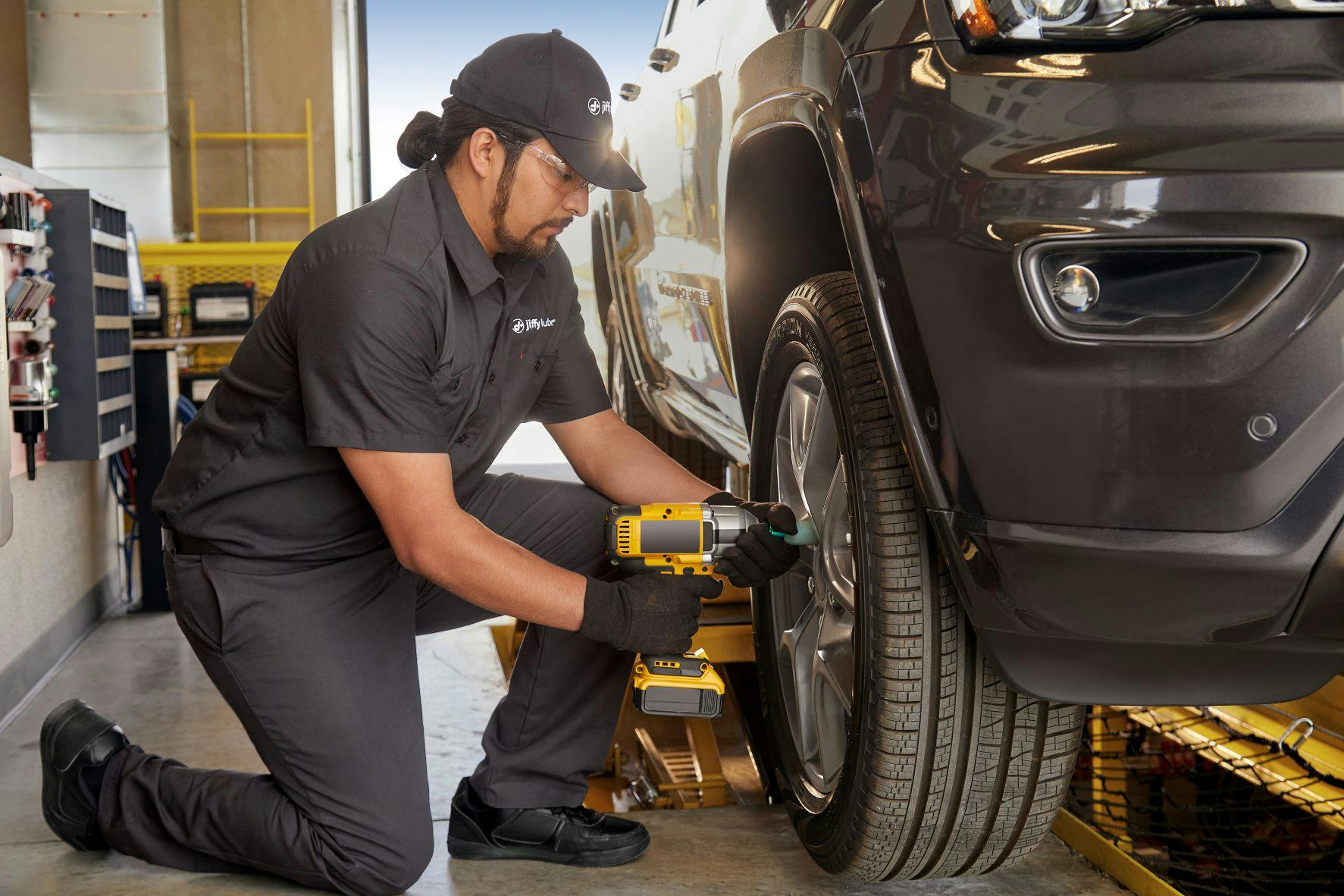 Jiffy Lube technician tightening lug nuts after rotating the tires on a vehicle