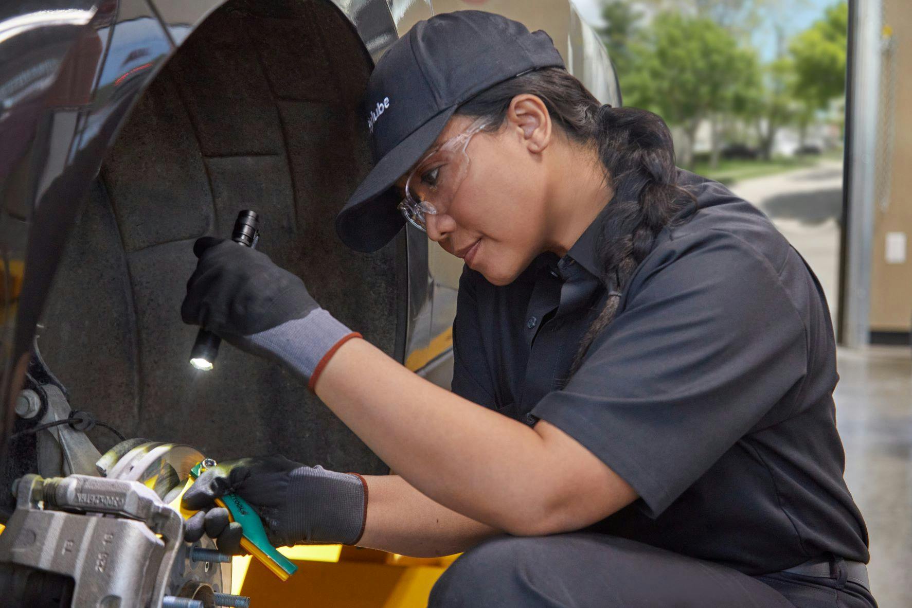 Service member using a flashlight to check a car's brake pads