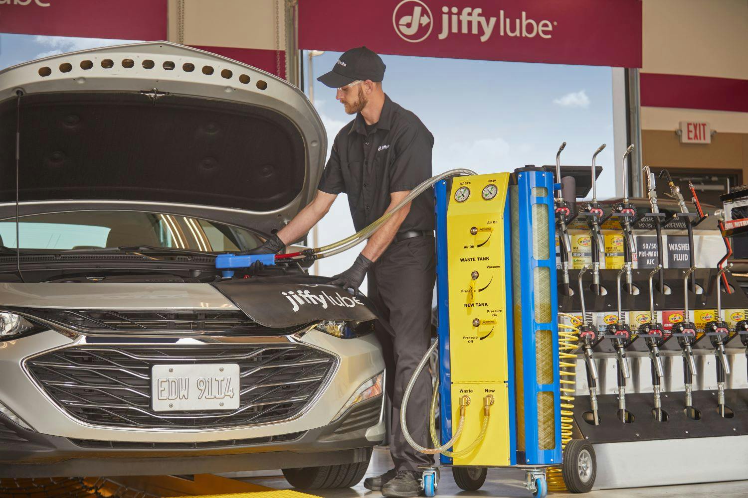 Jiffy Lube technician filling car engine coolant after completing a coolant flush