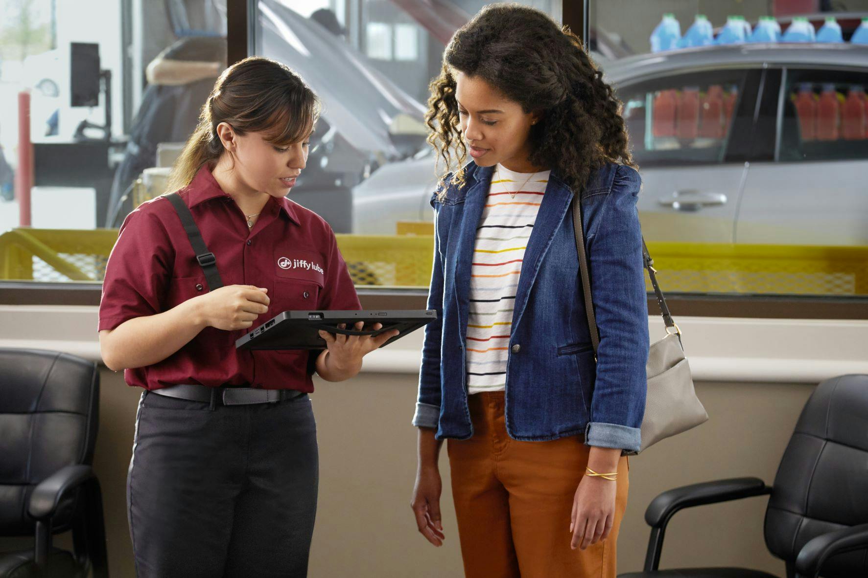 Jiffy Lube technician talking to a woman about her vehicle's spark plugs