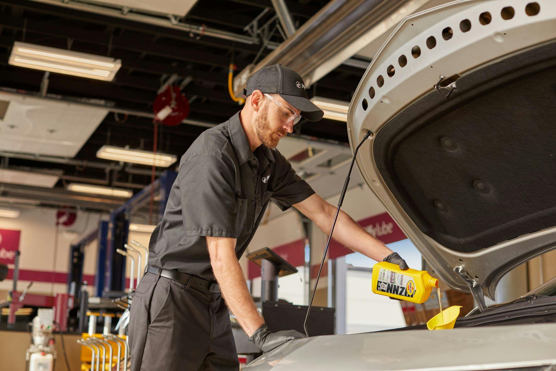 A Jiffy Lube technician changing a vehicle's oil with Pennzoil 