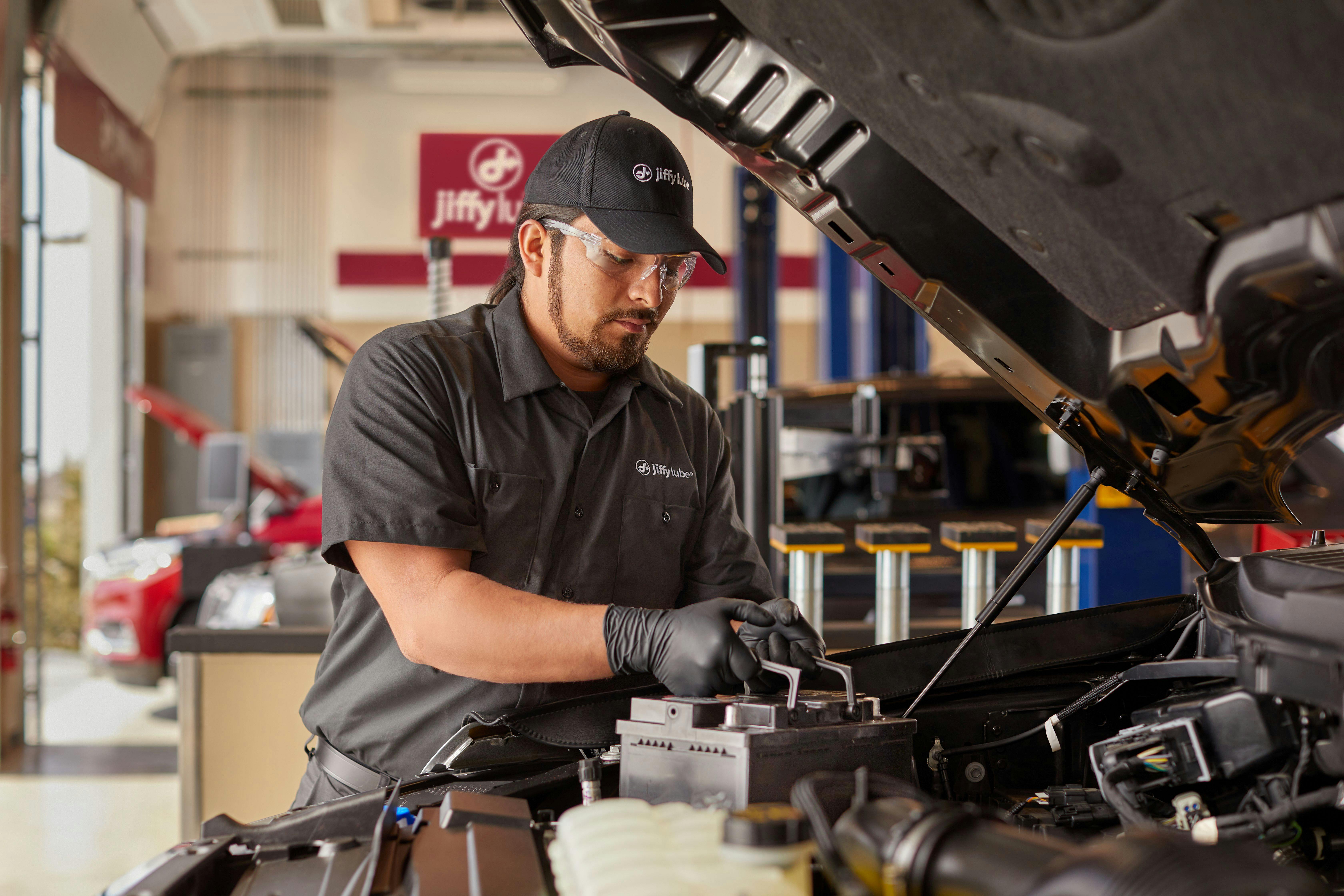 Jiffy Lube technician installing a new battery in a customer's car. 