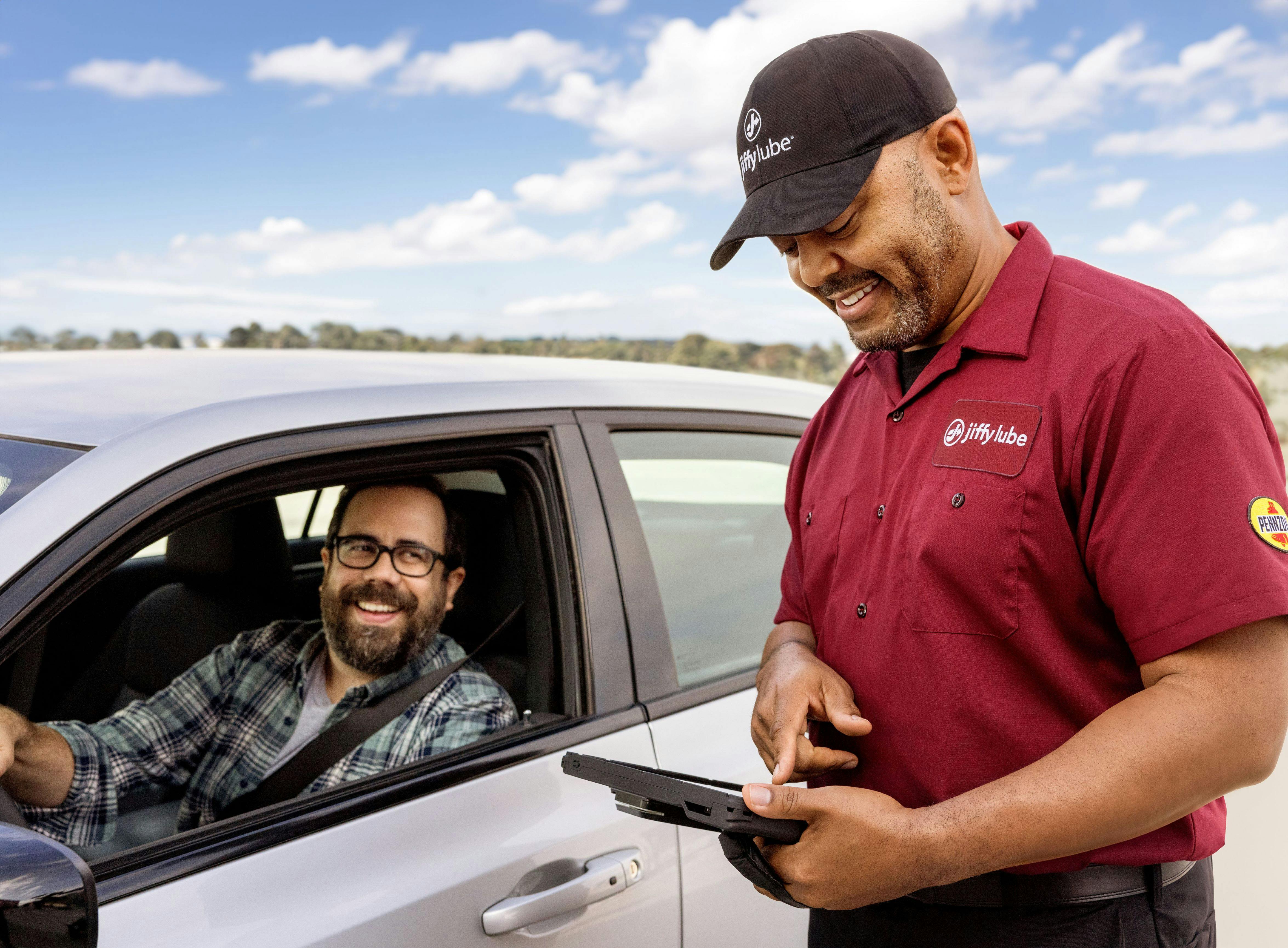 Jiffy Lube employee conversing with a customer in their car