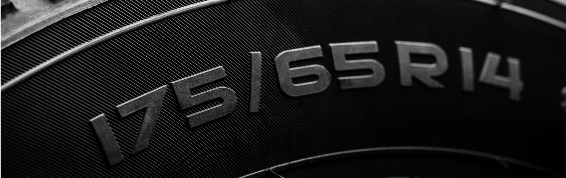 Close up on a new tire showing the tire size, aspect ratio, and wheel size