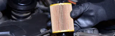 Close-up of a mechanic holding an oil filter during vehicle maintenance