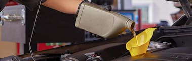 employee pouring oil into a yellow funnel