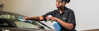 A Jiffy Lube technician cleaning a windshield after replacing a broken windshield