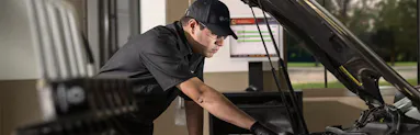 A Jiffy Lube technician is checking the amount of engine oil in a vehicle