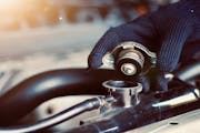 Jiffy Lube technician taking the cap off of radiator fluid