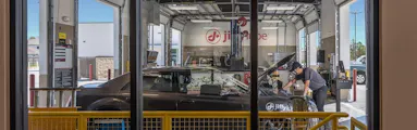 Technician servicing a car with its hood open inside a service bay
