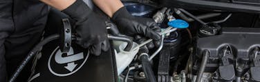 Jiffy Lube technician topping off windshield wiper fluid during an auto service