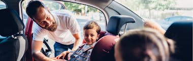 Father strapping in two children to taking them to school